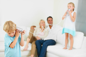 Image showing This really works. A little boy shouting loudly into a tin can connected to another that his sister is holding.