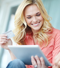 Image showing Oh wow, a sale. a beautiful young woman using her digital tablet and credit card to shop online.