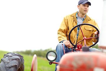 Image showing Providing for my family. A farmer driving his tractor on an open field.