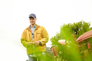 Image showing Alone in the countryside - Planning for the year ahead. a farmer standing in a field with his tractor next to him.