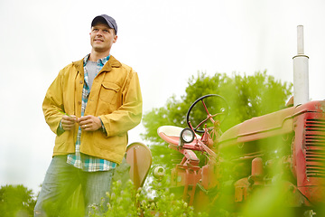 Image showing Nature is my office. a farmer standing in a field with his tractor beside him - Copyspace.