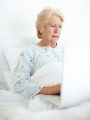 Image showing Technology keeps her connected with her loved ones. Elderly female patient browses a laptop from her hospital bed.