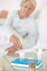 Image showing Daily dosage - Senior Health. Closeup of a daily medical dosage with woman reaching for it blurred in background.