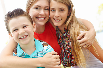 Image showing Spending time with her kids. Smiling mother embracing her teen daughter and young son while outdoors.