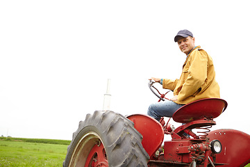 Image showing This is my job and I love it. Rearview of a smiling farmer driving his tractor on an open field with copyspace.