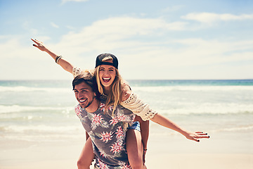 Image showing He makes me feel like Im flying. Portrait of an attractive young woman getting a piggyback from her boyfriend on the beach.