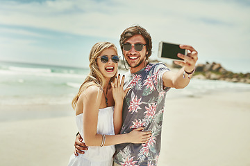 Image showing Guess whos engaged. an affectionate young couple taking selfies after their engagement on the beach.