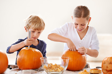 Image showing Brother and sister bonding. A brother and sister hollowing and carving pumpkins for halloween.