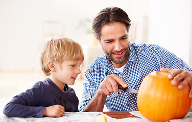 Image showing The final touch. A father and son carving a pumpkin at home for halloween.