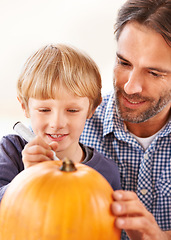 Image showing Ill carve it after you mark out the face. A father and son marking a pumpkin in the kitchen for halloween.