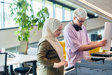 Image showing In a modern startup office, a business-minded Muslim woman wearing a hijab collaborates with her colleague, symbolizing diversity, empowerment, and success in the contemporary corporate world