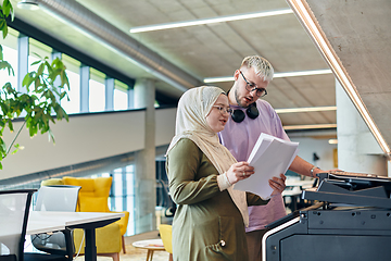 Image showing In a modern startup office, a business-minded Muslim woman wearing a hijab collaborates with her colleague, symbolizing diversity, empowerment, and success in the contemporary corporate world