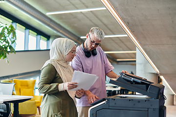 Image showing In a modern startup office, a business-minded Muslim woman wearing a hijab collaborates with her colleague, symbolizing diversity, empowerment, and success in the contemporary corporate world