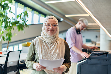 Image showing In a modern startup office, a business-minded Muslim woman wearing a hijab collaborates with her colleague, symbolizing diversity, empowerment, and success in the contemporary corporate world