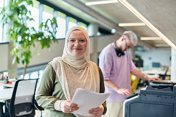 Image showing In a modern startup office, a business-minded Muslim woman wearing a hijab collaborates with her colleague, symbolizing diversity, empowerment, and success in the contemporary corporate world