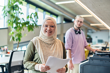 Image showing In a modern startup office, a business-minded Muslim woman wearing a hijab collaborates with her colleague, symbolizing diversity, empowerment, and success in the contemporary corporate world