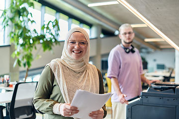 Image showing In a modern startup office, a business-minded Muslim woman wearing a hijab collaborates with her colleague, symbolizing diversity, empowerment, and success in the contemporary corporate world