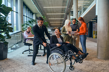 Image showing A diverse group of business colleagues is having fun with their wheelchair-using colleague, demonstrating their attention and inclusivity in the workplace