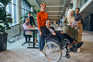 Image showing A diverse group of business colleagues is having fun with their wheelchair-using colleague, demonstrating their attention and inclusivity in the workplace