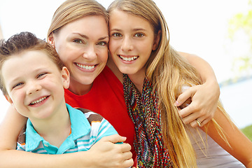 Image showing Spending time with mom. Smiling mother embracing her teen daughter and young son while outdoors.