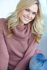 Image showing Portrait of a beautiful blonde woman relaxing at home on the sofa in the lounge. Cheerful female sitting on the couch in the living room alone on the weekend. Comfy, smiling and resting inside