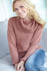 Image showing Portrait of a beautiful blonde woman relaxing at home on the sofa in the lounge. Cheerful female sitting on the couch in the living room alone on the weekend. Comfy, smiling and resting inside