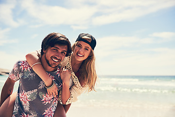 Image showing Were a couple of beach lovers. Portrait of an attractive young woman getting a piggyback from her boyfriend on the beach.