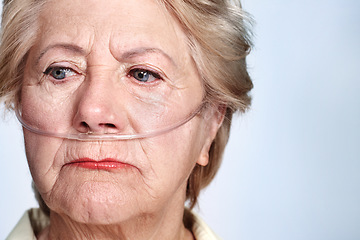 Image showing Illness and regret. Closeup of a sickly senior woman wearing a nasal cannula for oxygen isolated on blue - Copyspace.