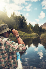 Image showing Hes always searching for a new adventure. Rearview shot of a young man looking through his binoculars while enjoying a canoe ride on the lake.