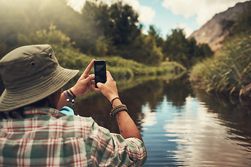 Image showing Scenic snapshots are essential. Rearview shot of a young man taking photos on his cellphone while enjoying a canoe ride on the lake.