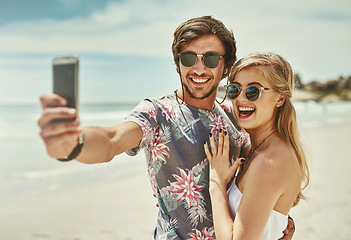 Image showing She said yes. an affectionate young couple taking selfies after their engagement on the beach.