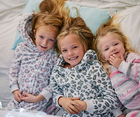 Image showing Little cuties. Portrait of three little sisters lying in bed together at home.