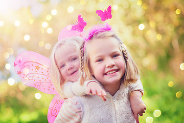 Image showing This little fairy just needs some help practising to fly. Portrait of two little sisters dressed up as fairies and having fun outside.