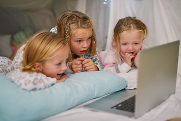 Image showing Its their favourite cartoon to watch before bed. three little sisters watching something on a laptop before bedtime.