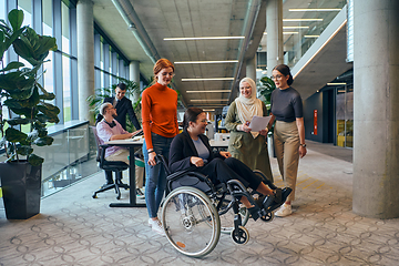 Image showing A diverse group of business colleagues is having fun with their wheelchair-using colleague, demonstrating their attention and inclusivity in the workplace