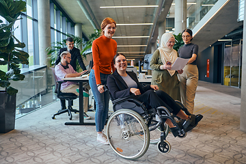 Image showing A diverse group of business colleagues is having fun with their wheelchair-using colleague, demonstrating their attention and inclusivity in the workplace