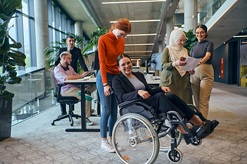 Image showing A diverse group of business colleagues is having fun with their wheelchair-using colleague, demonstrating their attention and inclusivity in the workplace