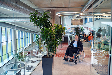 Image showing In a modern office, a young businesswoman in a wheelchair is surrounded by her supportive colleagues, embodying the spirit of inclusivity and diversity in the workplace