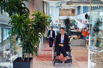 Image showing In a modern office, a young businesswoman in a wheelchair is surrounded by her supportive colleagues, embodying the spirit of inclusivity and diversity in the workplace