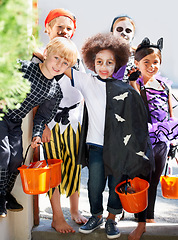 Image showing Our pales are full of candy. Portrait of a group of little children trick-or-treating on halloween.