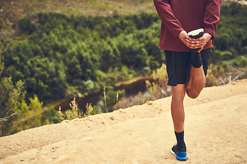 Image showing Preparing his legs for a workout. Rearview shot of a young man warming up before a trail run.