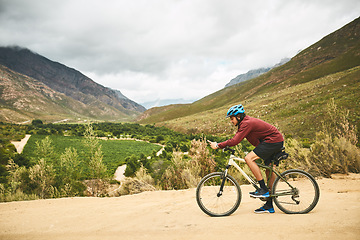 Image showing Tracking his exact location via GPS. a young man using his cellphone while cycling along a trail.