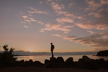 Image showing The rewards of trekking unknown paths is unmeasurable. a man wearing his backpack while out for a hike on a coastal trail.