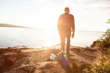 Image showing The physical benefits of hiking is numerous. a man wearing his backpack while out for a hike on a coastal trail.