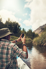 Image showing Soaking up the scenic views. Rearview shot of a young man taking photos on his cellphone while enjoying a canoe ride on the lake.