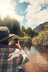 Image showing Itll be an adventure to remember. Rearview shot of a young man taking photos on his cellphone while enjoying a canoe ride on the lake.