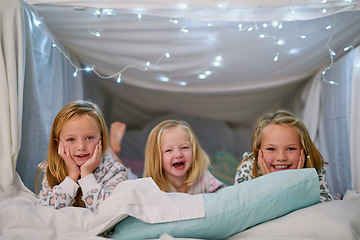 Image showing Three little cuties all lined up in bed. Portrait of three little sisters lying in bed together at home.