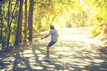 Image showing The life of a skater is far from boring. Rearview shot of a young man longboarding in the street.