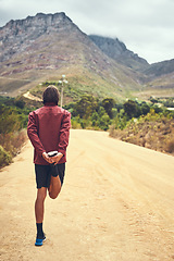 Image showing The best runs are those with spectacular views. Rearview shot of a young man warming up before a trail run.