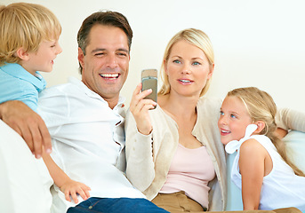 Image showing Do you remember this. a woman showing her husband her phone while their two children sit next to them.